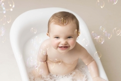 Playing with bubbles in the bath after a cake smash and bath splash session at Wirral Merseyside  photo studio