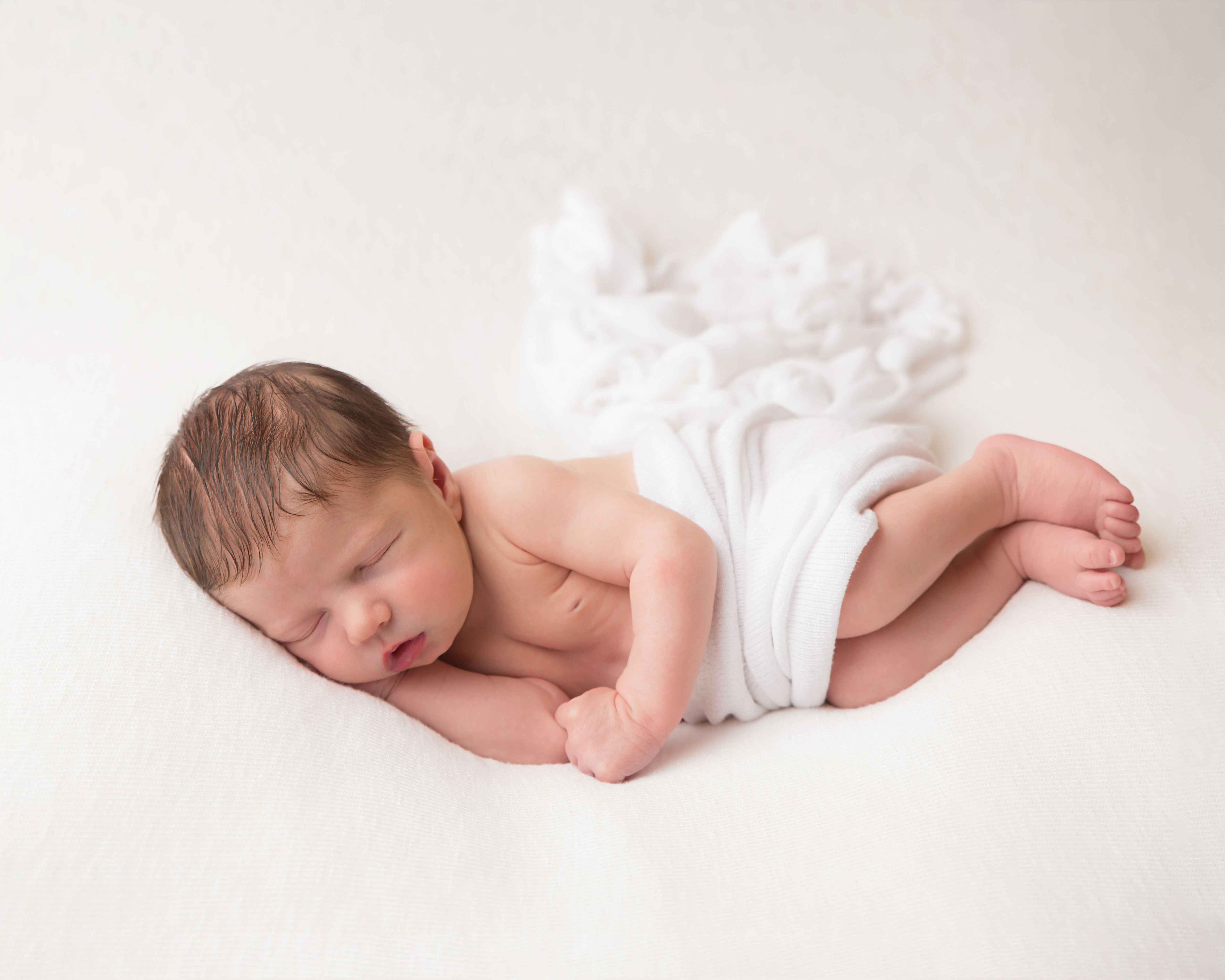 Baby's head resting on hand, sweeping blanket in natural colour