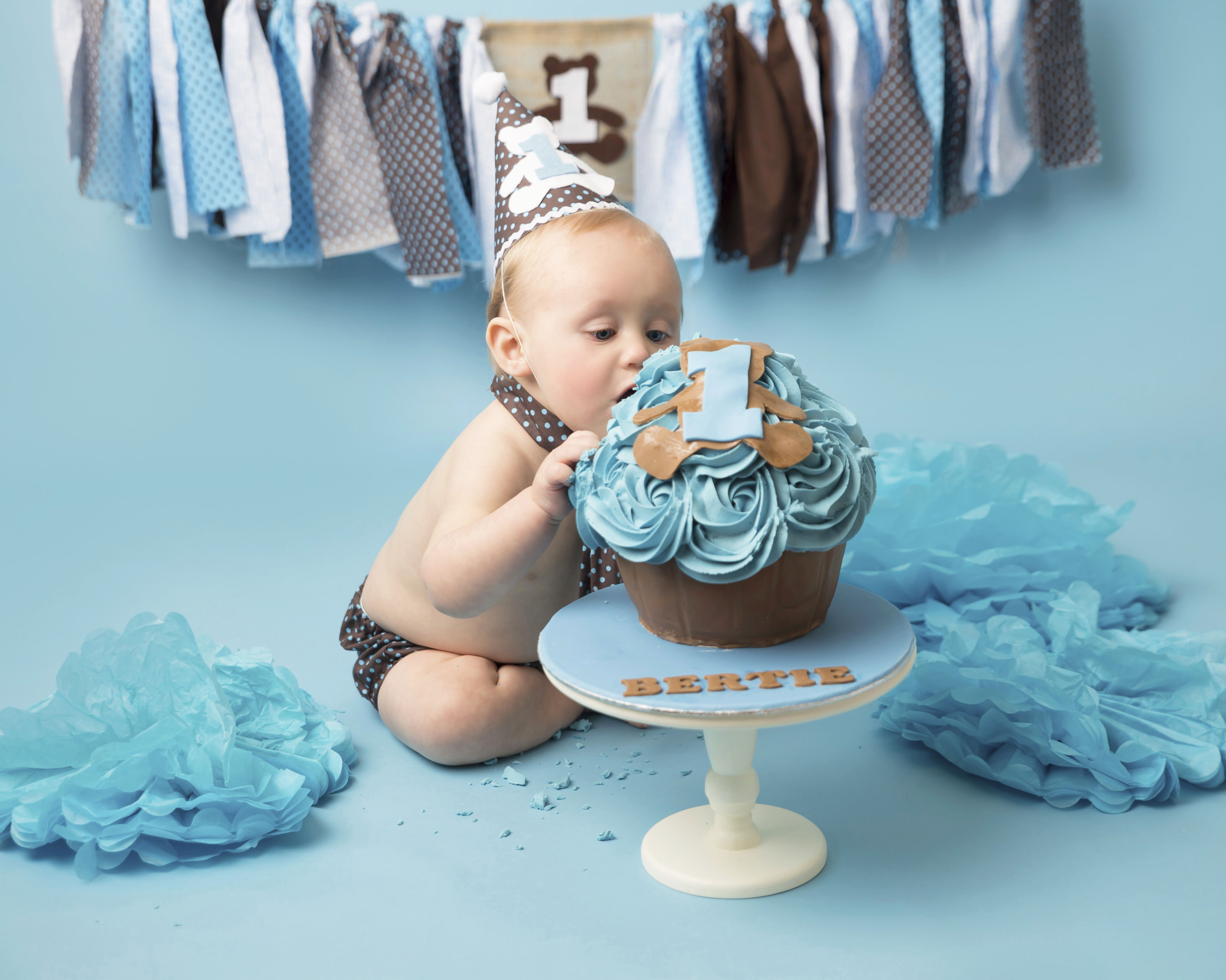 Bear Themed Cake Smash, cake with blue icing along with brown matching costume and bunting