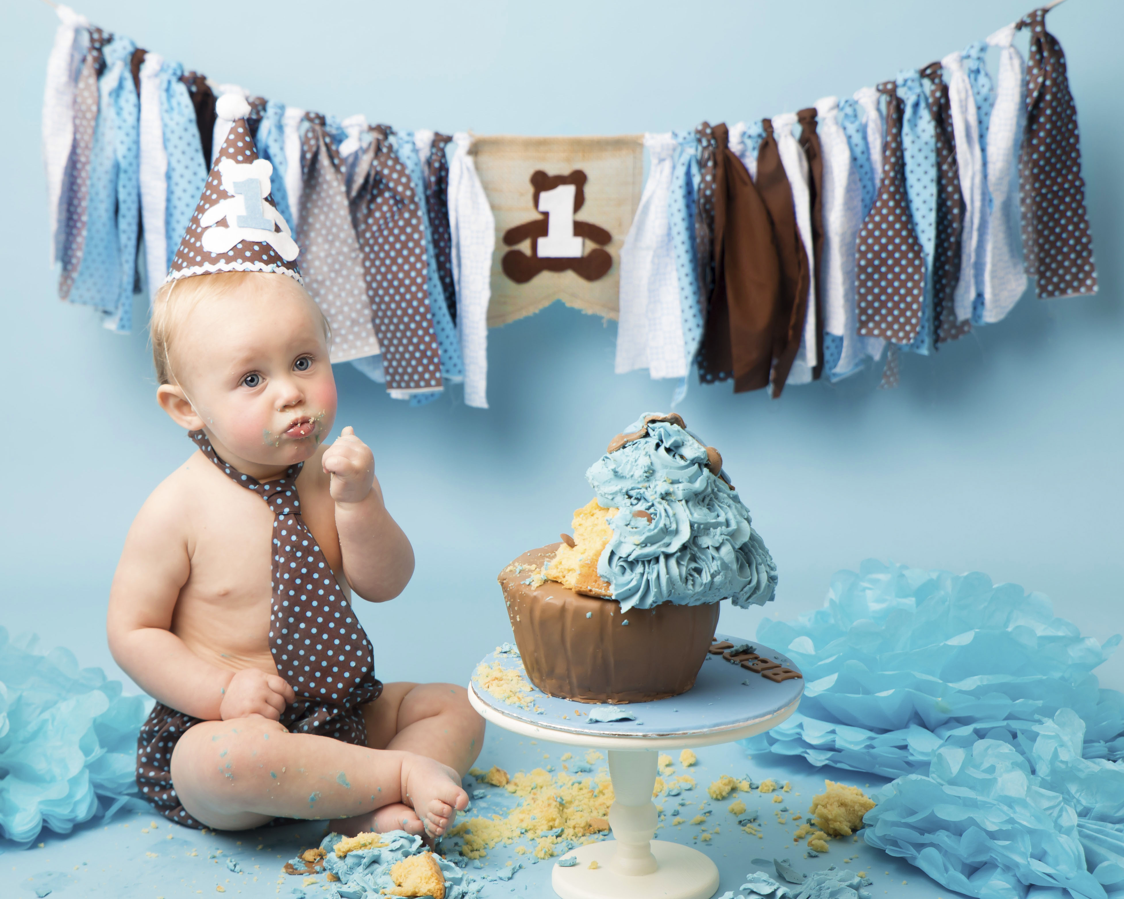 Bear Themed Cake Smash, cake with blue icing along with brown matching costume and bunting